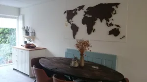 grote palissander wereldkaart op een witte achterplaat op de muur boven de eettafel