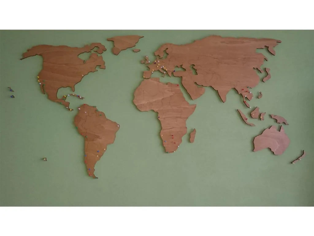 Grote houten wereldkaart aan de muur met prikkers voor bezochte landen